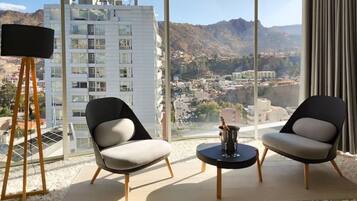 Una habitación moderna con dos sillas, una mesita y un ventanal con vistas a la ciudad.