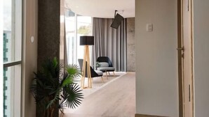 Een moderne hal met een houten vloer, een plant in een pot en een stoel op de achtergrond.