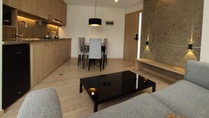 Een moderne keuken met houten kastjes, een eethoek met tafel en stoelen, en een zithoek met een bank en salontafel.