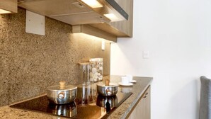 Een keuken met granieten aanrechtbladen, roestvrijstalen apparatuur en houten kastjes.