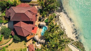 An aerial view of a coastal property with a swimming pool, a thatched-roof structure, and a beach. - Ocean View Private Beach Villa 2 Pools 7 Ensuite Bedrooms Fully Staffed (Makunduchi)
