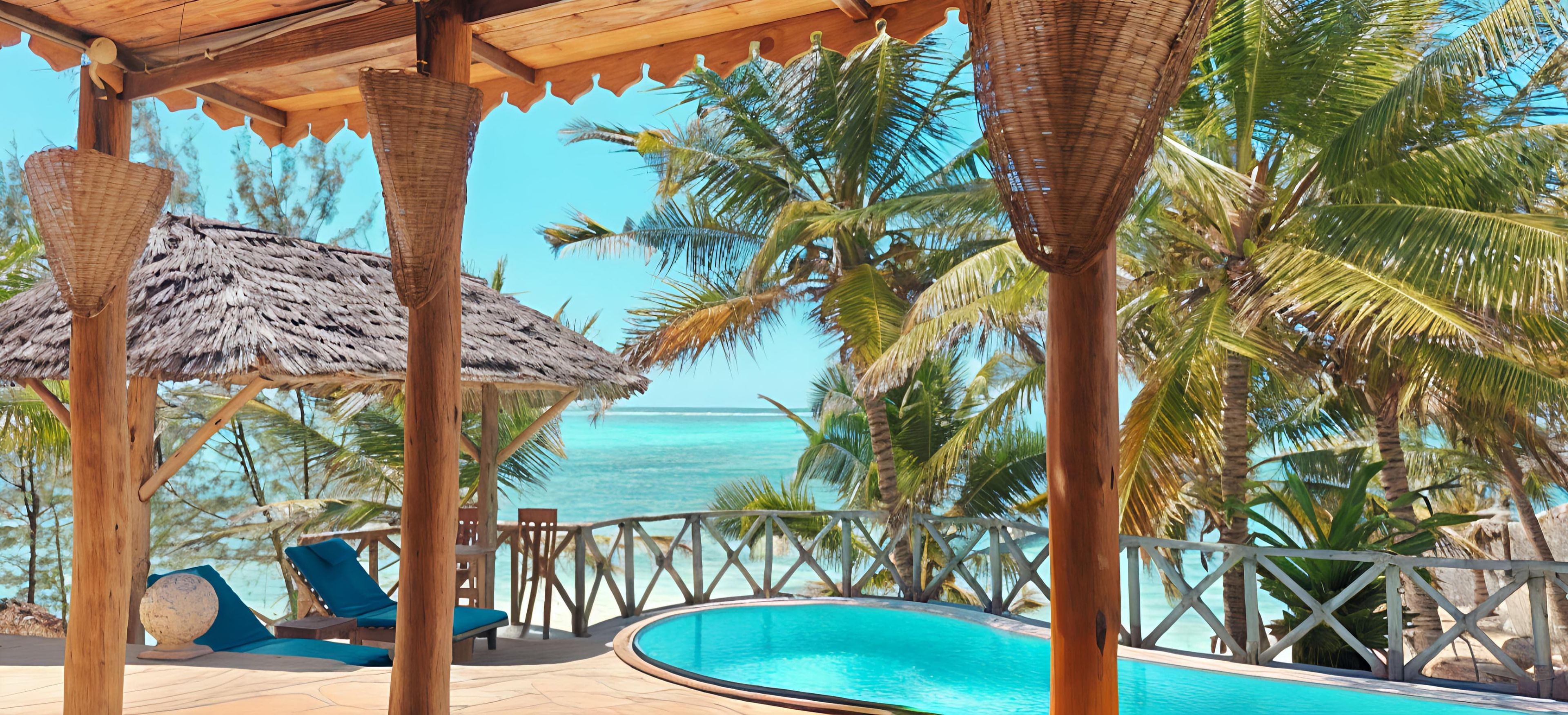A poolside area with a thatched roof, lounge chairs, and a view of the ocean.