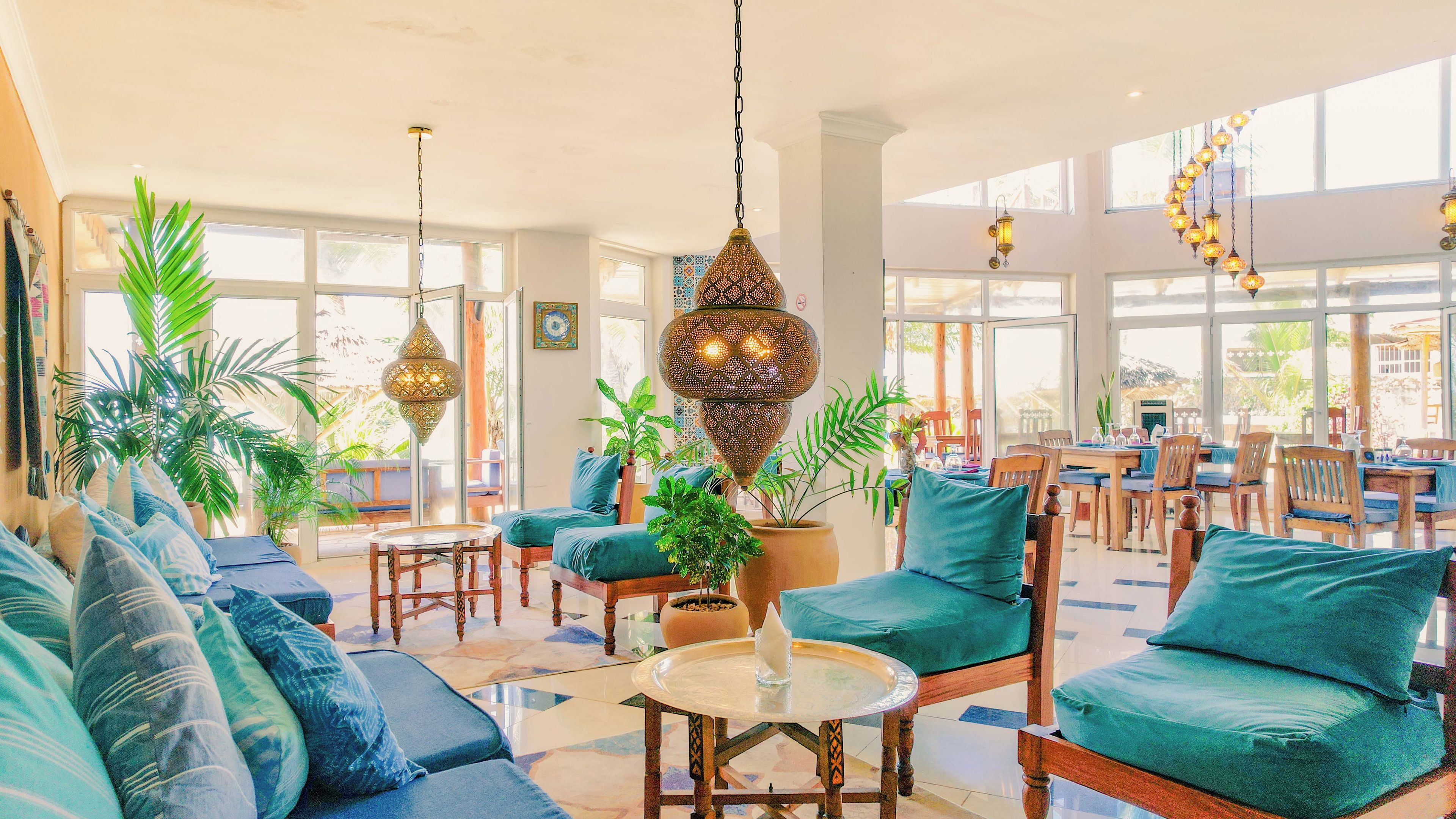 A spacious lounge area with a high ceiling, large windows, and a variety of seating arrangements including sofas and chairs.