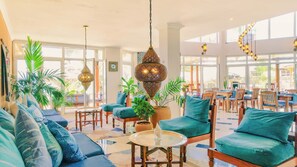 A spacious lounge area with a high ceiling, large windows, and a variety of seating arrangements including sofas and chairs. - Ocean View Private Beach Villa 2 Pools 7 Ensuite Bedrooms Fully Staffed (Makunduchi)