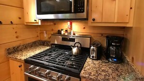 Une cuisine équipée d’une cuisinière en acier inoxydable, d’un four à micro-ondes, d’une bouilloire et d’une machine à café.