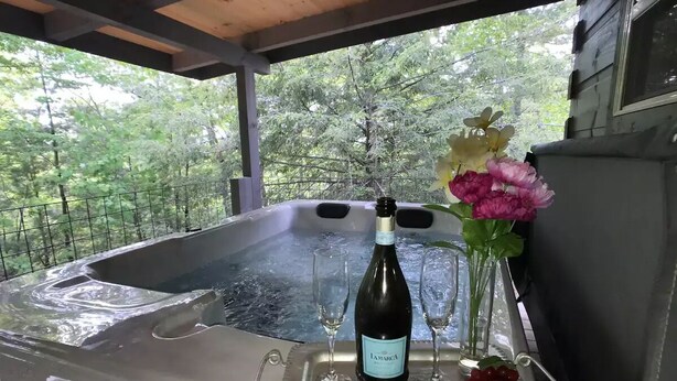Un bain à remous avec une bouteille de vin, des verres et des fleurs.