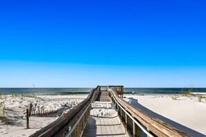 Walk along the boardwalk to the sandy beach, where lush vegetation meets the shore.