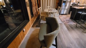 A modern kitchen with stainless steel appliances, a dining area with a table and chairs, and a large window with curtains. - Tranquil Riverside Lodge (Wade)