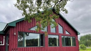 A red wooden building with large windows and a green roof. - Tranquil Riverside Lodge (Wade)