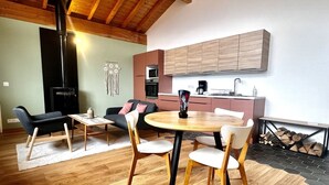 Un espai de vida modern amb sòl de fusta, taula de dinar rodona i zona de cuina amb armaris de fusta.