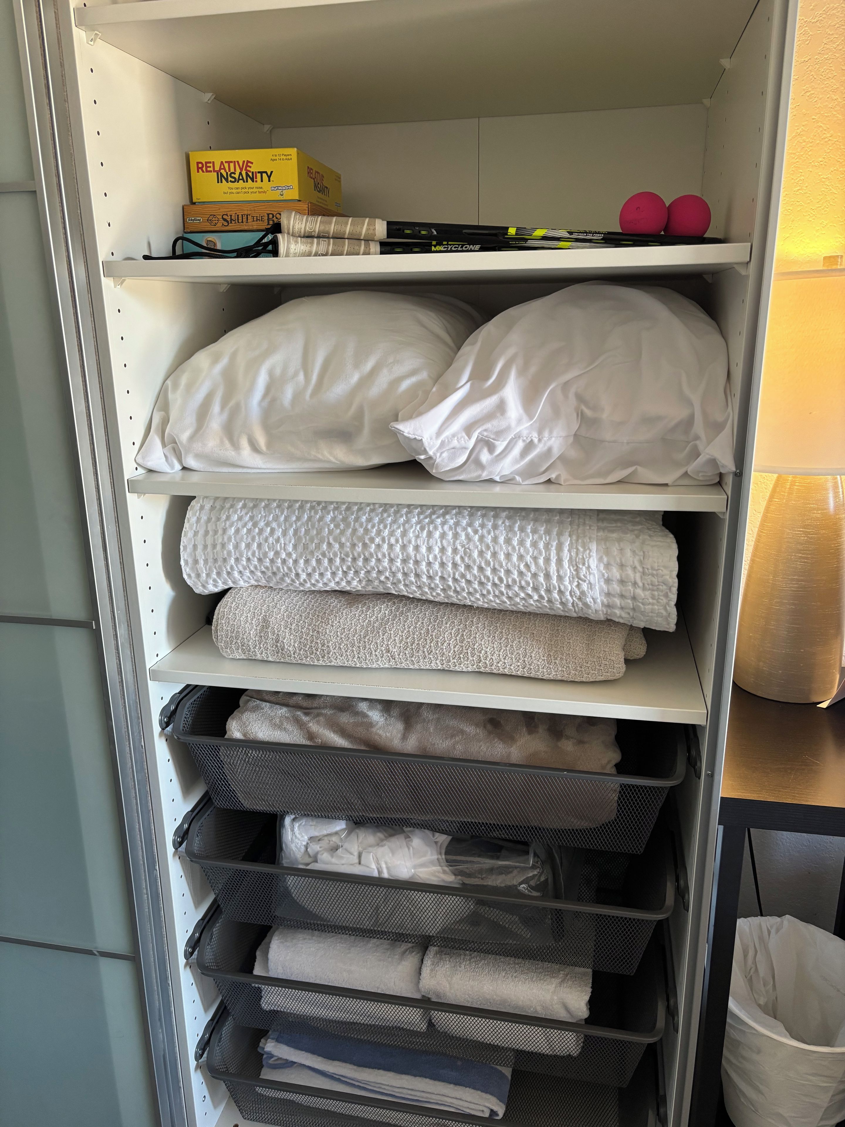 Ein Abstellraum mit Regalen, voll mit Kissen, Bettwäsche und Aufbewahrungsboxen.