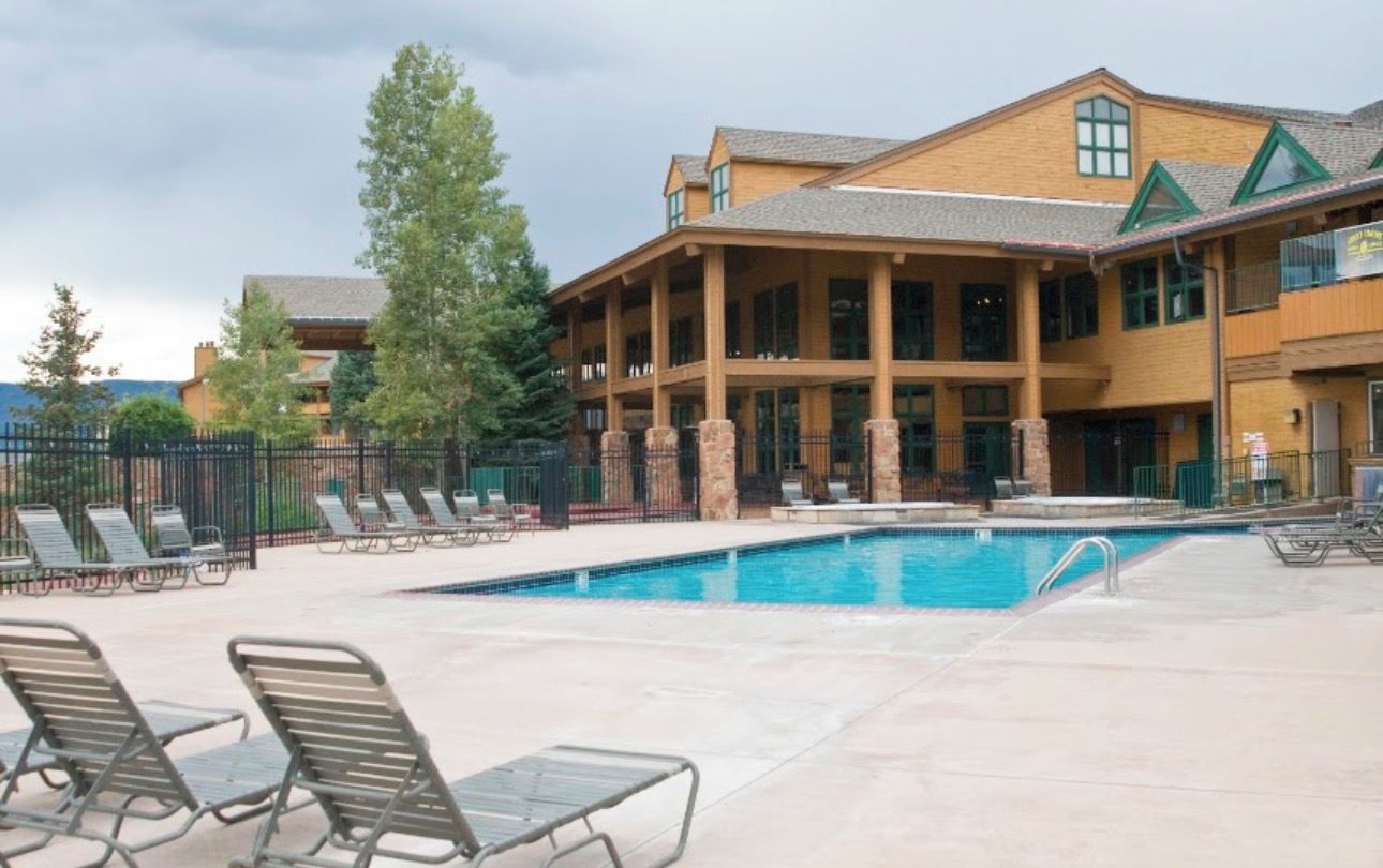Ein Hotel mit Poolbereich, Liegestühlen und einem Gebäude mit zahlreichen Fenstern und Balkonen.