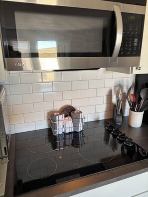 A kitchen with a black induction cooktop, a stainless steel microwave above it, and a white tiled backsplash. - Centrally Located Studio just minutes from Granby, Colorado (Granby)
