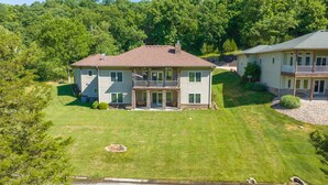 A two-story house with a front porch, a covered patio, and a well-maintained lawn. - Overlooking 9th Green at Osage National Golf Resort (Lake Ozark)