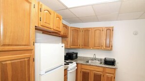 Une cuisine de taille réduite, avec des meubles en bois, un réfrigérateur blanc, une cuisinière et un four à micro-ondes.