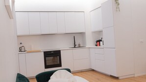 Una cocina compacta con armarios blancos, un horno negro y una pequeña encimera.
