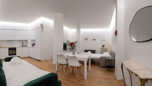 Una habitación moderna y bien iluminada con zona de comedor, sofá y cama.