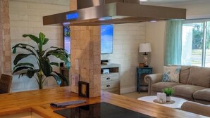 A modern kitchen with a wooden countertop, built-in oven, and a stainless steel range hood. - The Sand Castle - Backyard Oasis Mins from Siesta! (Sarasota)