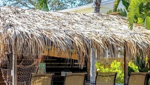 A thatched-roof outdoor seating area with four wicker chairs and a bar counter. - The Sand Castle - Backyard Oasis Mins from Siesta! (Sarasota)