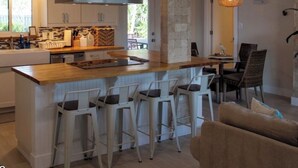 A modern kitchen with a central island, bar stools, and a dining area with chairs. - The Sand Castle - Backyard Oasis Mins from Siesta! (Sarasota)