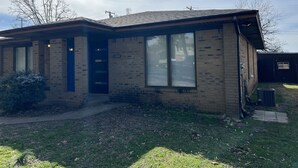 A single-story brick building with a flat roof, large windows, and a visible address number. - Retro Centrally Located Duplex! (Fort Smith)