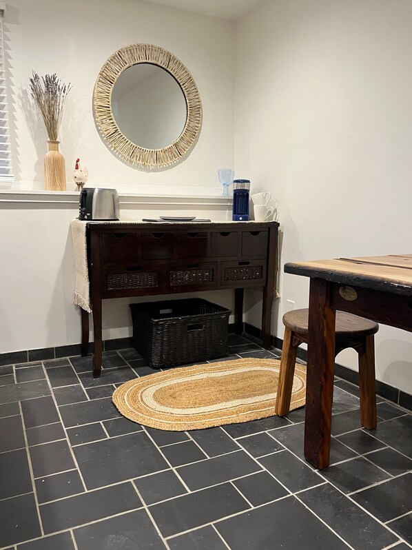 A kitchen with a dark wooden table, a round mirror, and a woven rug on a tiled floor. - Scituate Harbor Escape! (Scituate)
