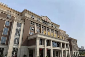 Un edificio grande de varios pisos con una entrada destacada, ventanas amplias y techo plano.