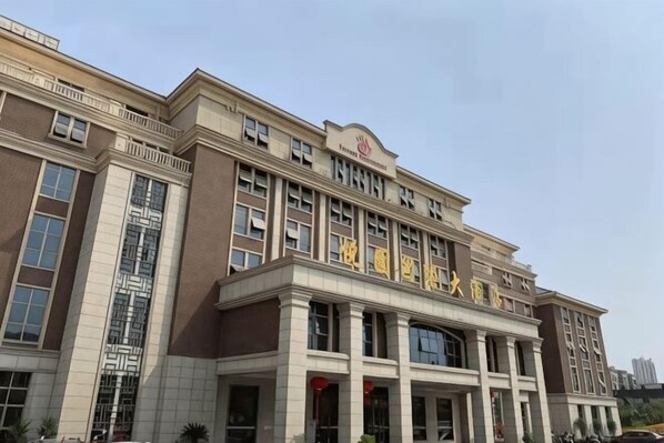 A large, multi-story building with a prominent entrance, large windows, and a flat roof.