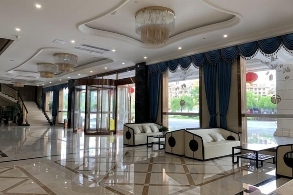 A spacious lobby with a marble floor, a staircase, and a seating area with sofas.