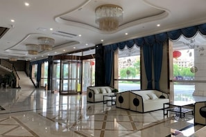 Un hall dâentrĂ©e spacieux, agrĂ©mentĂ© dâun magnifique lustre, dâun escalier et dâun coin salon offrant une vue sur lâextĂ©rieur.