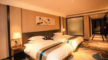 Habitación de hotel con dos camas, una mesita de noche con lámpara, un cuadro en la pared y un espejo grande.