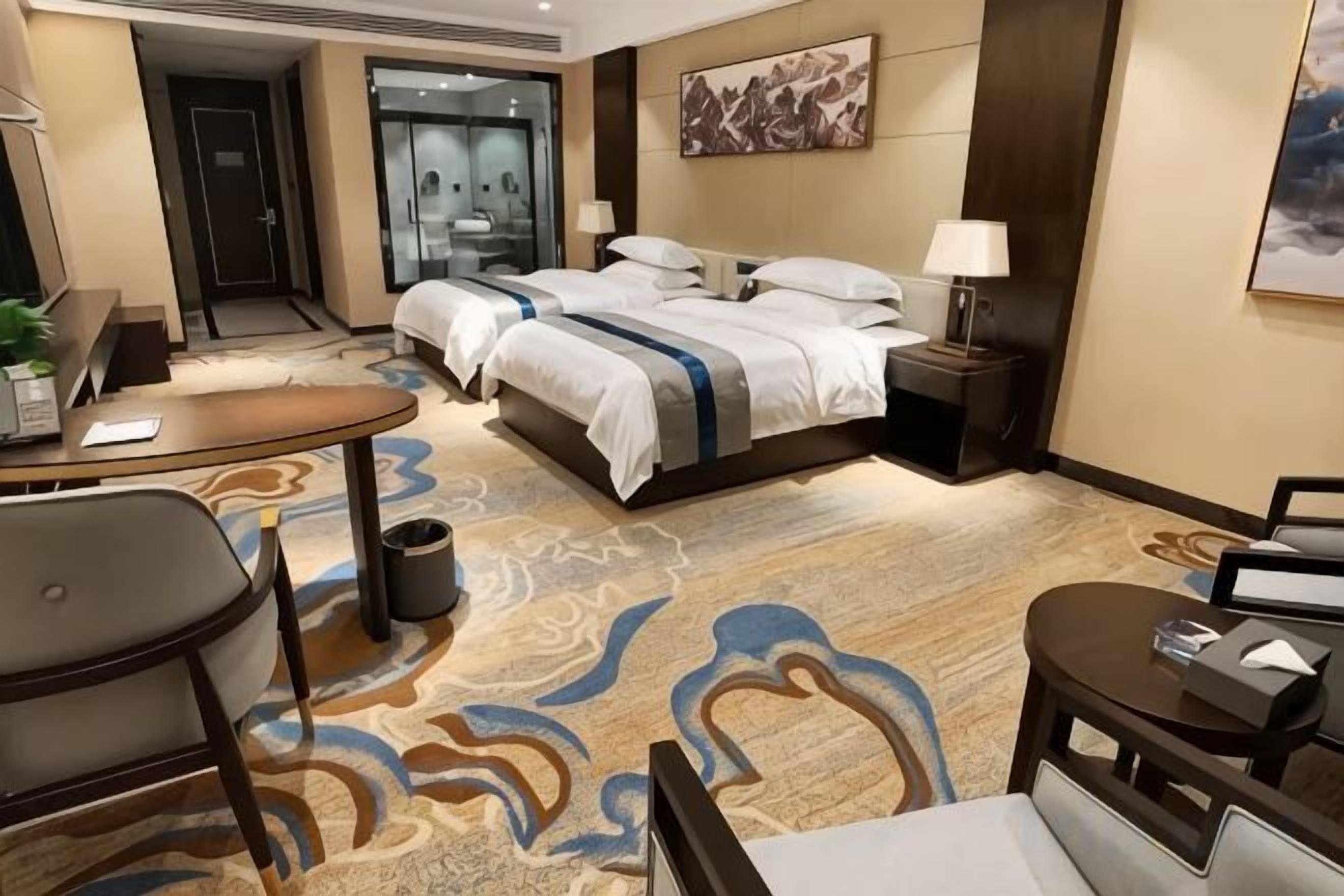 A hotel room with a bed, bedside tables, a desk, and a chair.