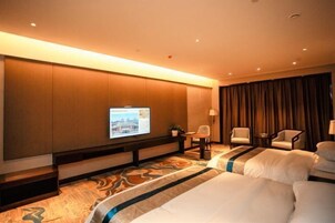 Habitación de hotel con una cama grande, un televisor en la pared, un escritorio con una silla y vista a la ciudad desde la ventana.