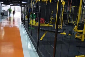 A gym with exercise equipment, a yellow and black color scheme, and a person walking in the distance. - Yueyuan International Hotel (Ningguo)