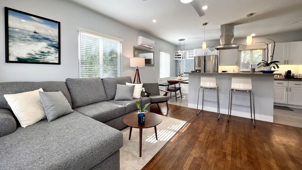 Una sala de estar moderna con un sofá gris, una mesita de centro y un comedor con una pequeña isla.