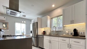 Una cocina moderna con armarios blancos, electrodomésticos de acero inoxidable y una isla grande.