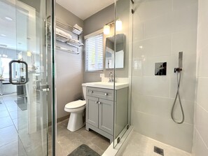 Ein modernes Badezimmer mit einer Duschkabine aus Glas, einer Toilette und einem Waschtisch mit Spiegel.