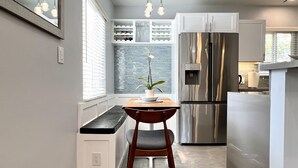 Una cocina moderna con refrigerador empotrado, una zona de comedor con banco y una planta en maceta.