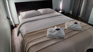 Una habitación de hotel con una cama, una mesita de noche y una lámpara fijada a la pared.