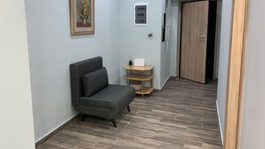 Un pasillo con un sofá gris, una pequeña mesa de madera y un cuadro enmarcado en la pared.