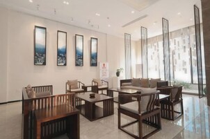 Un moderno vestíbulo de hotel con arreglos de asientos, un mostrador de recepción y ventanas amplias.
