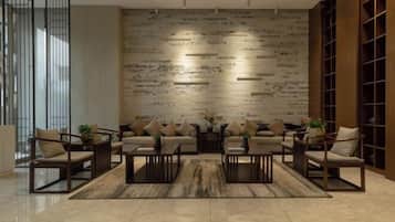 A modern living room with a sofa set, coffee tables, and a patterned wall.