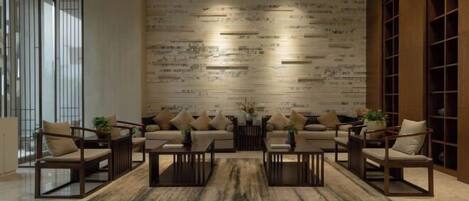 A modern living room with a sofa set, coffee tables, and a patterned wall.