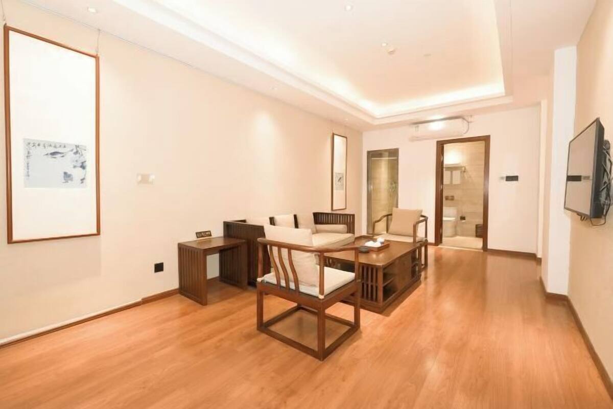A modern living room with wooden furniture, a flat-screen TV, and artwork on the walls.