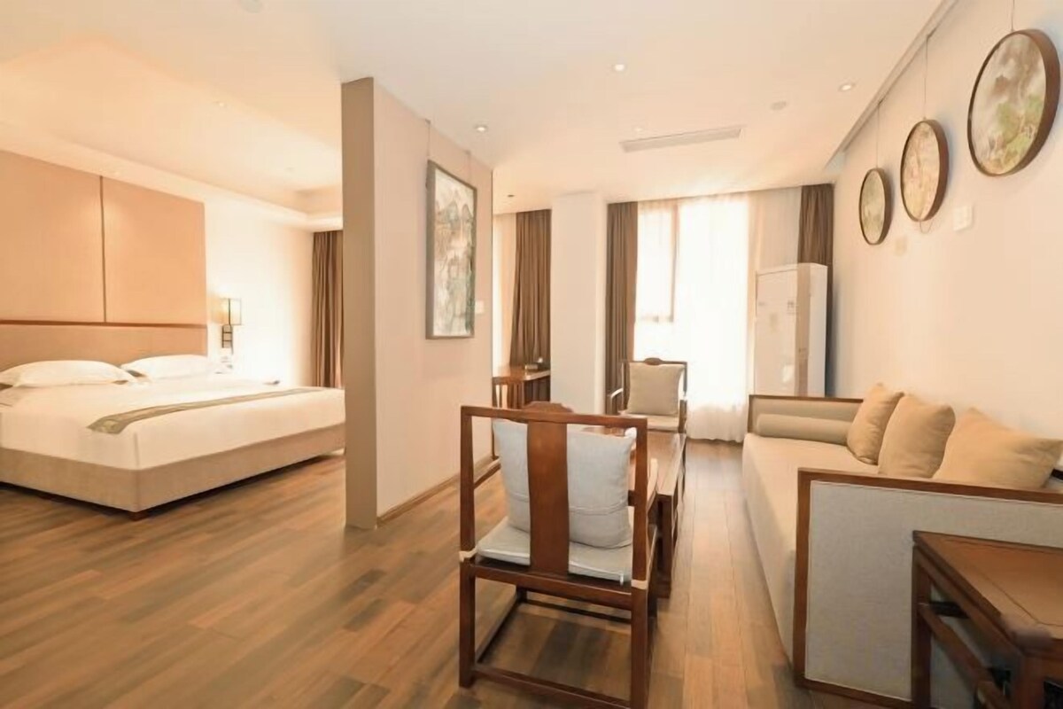 Una habitación de hotel con cama, zona de estar con mesa y sofá.