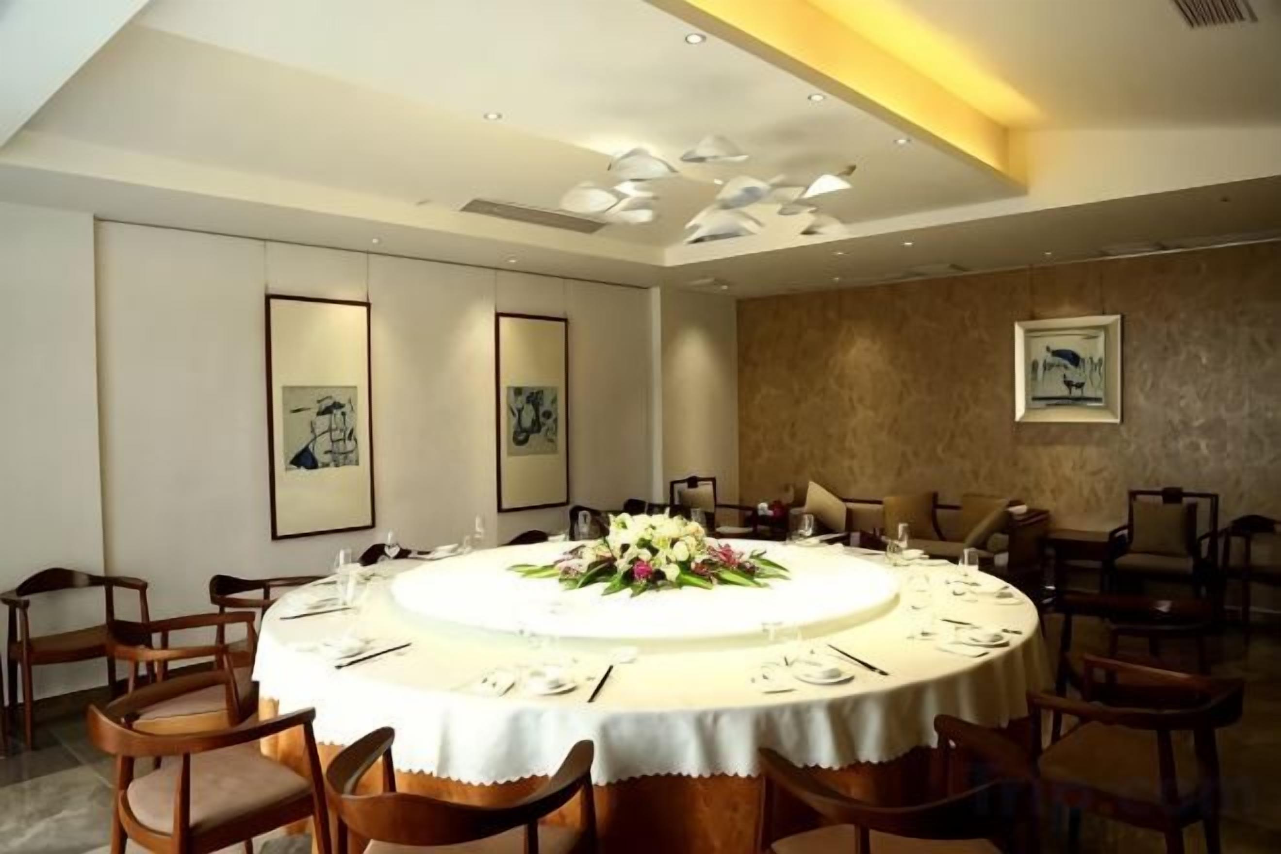 A conference room with a round table, chairs, and a floral centerpiece.