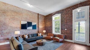 Een ruime woonkamer met een bakstenen muur, een groot raam en een moderne zithoek.