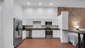 Een moderne keuken met witte kasten, roestvrijstalen apparatuur en een houten vloer.