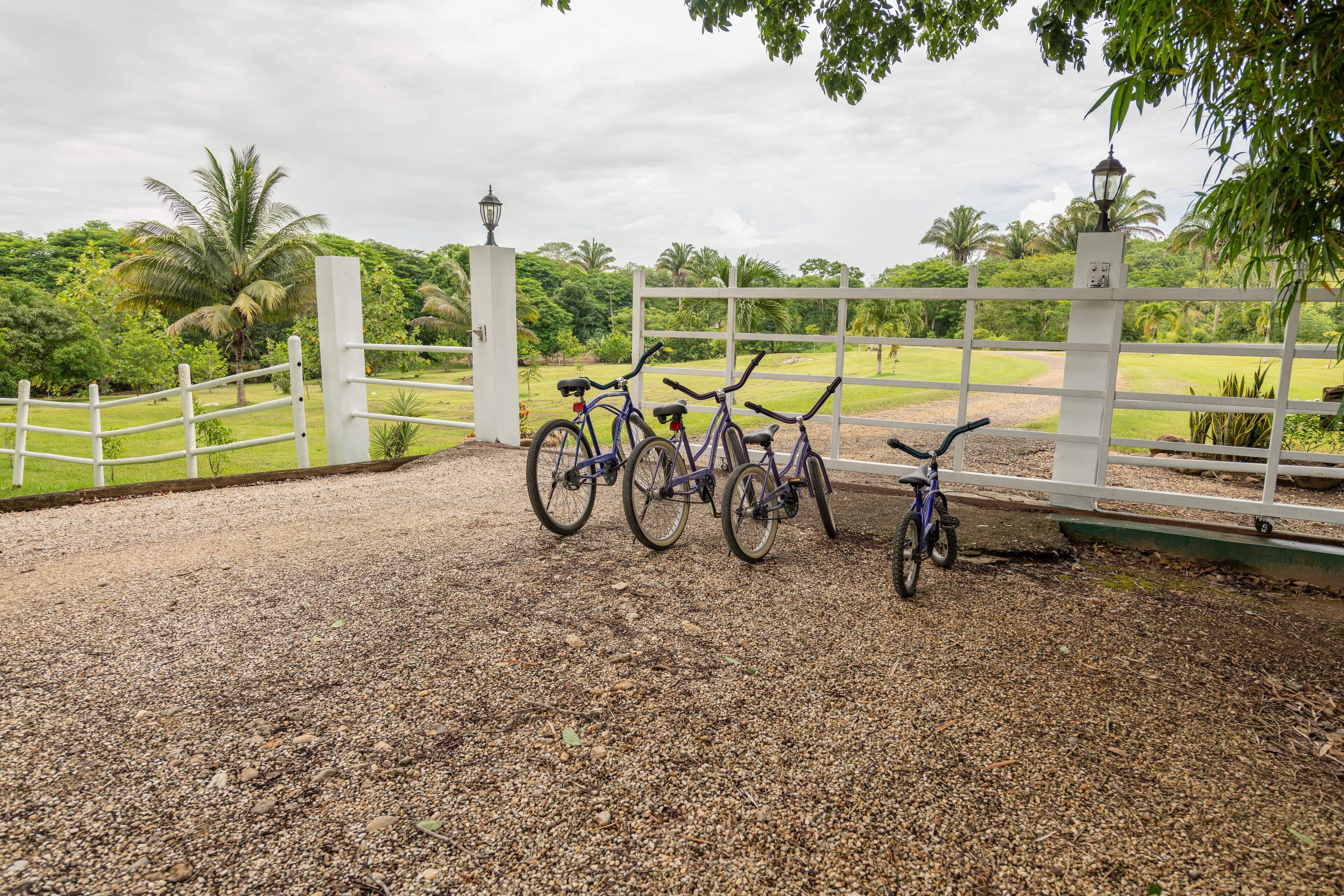 Bicycles parked near a white fence with a lamp post in a garden area.
