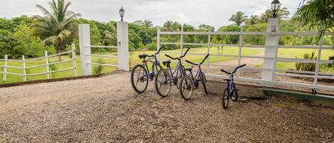Bicycles parked near a white fence with a lamp post in a garden area.